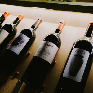 Close-up view of assorted wine bottles on a stylish wooden display shelf.