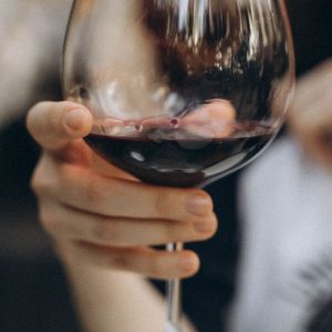 Close-up shot of hand holding a glass of red wine, showcasing elegance and luxury.